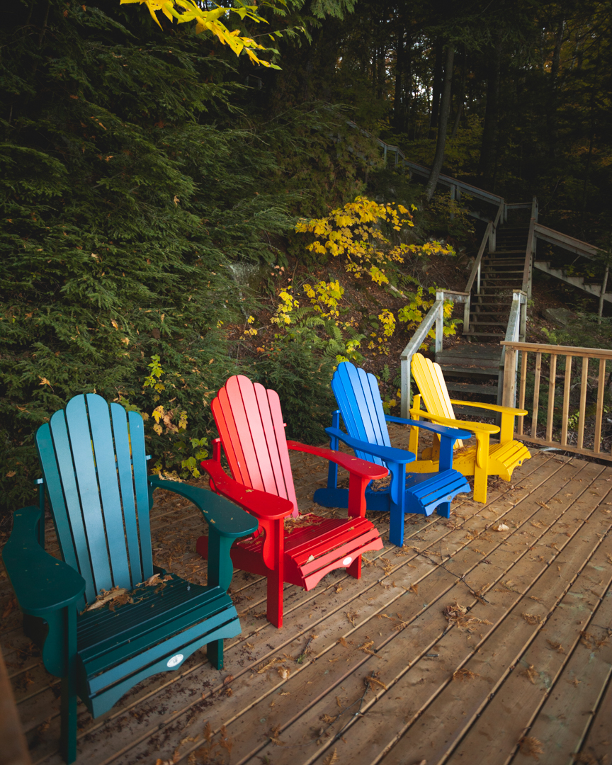 green red blue and yellow muskoka chairs on deck