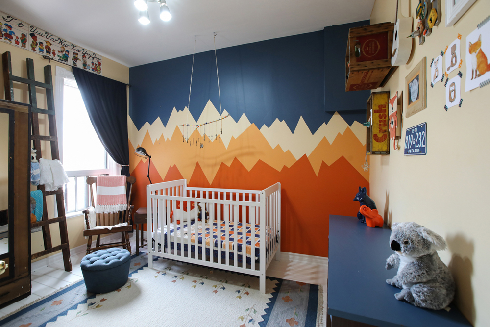 nursery with crib in front of blue rust and orange mountainscape focal wall