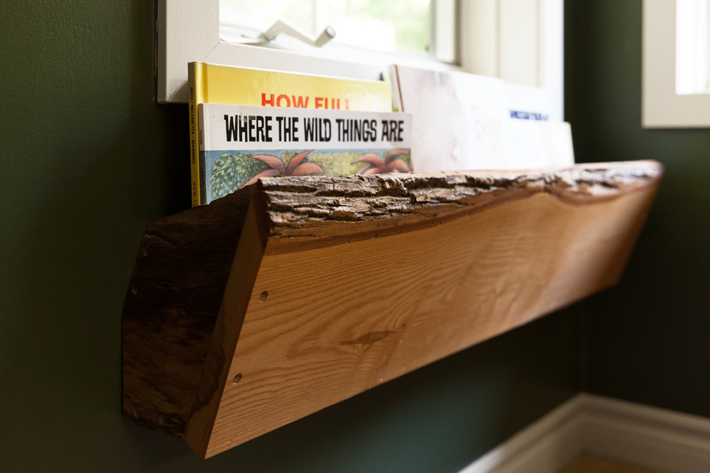 A wood book ledge beneath the window in a kids' bedroom
