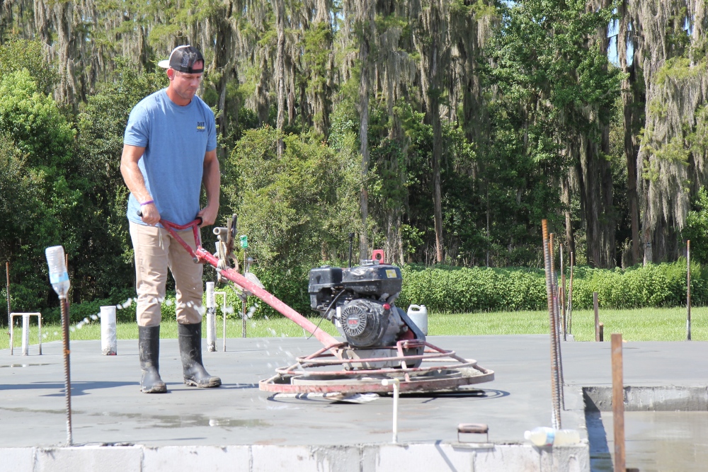 Brian Kleinschmidt is smoothing out the concrete for a farmhouse-style house foundation.