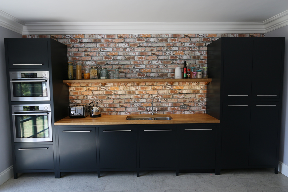 Distressed brick backsplash against sleek black cabinetry