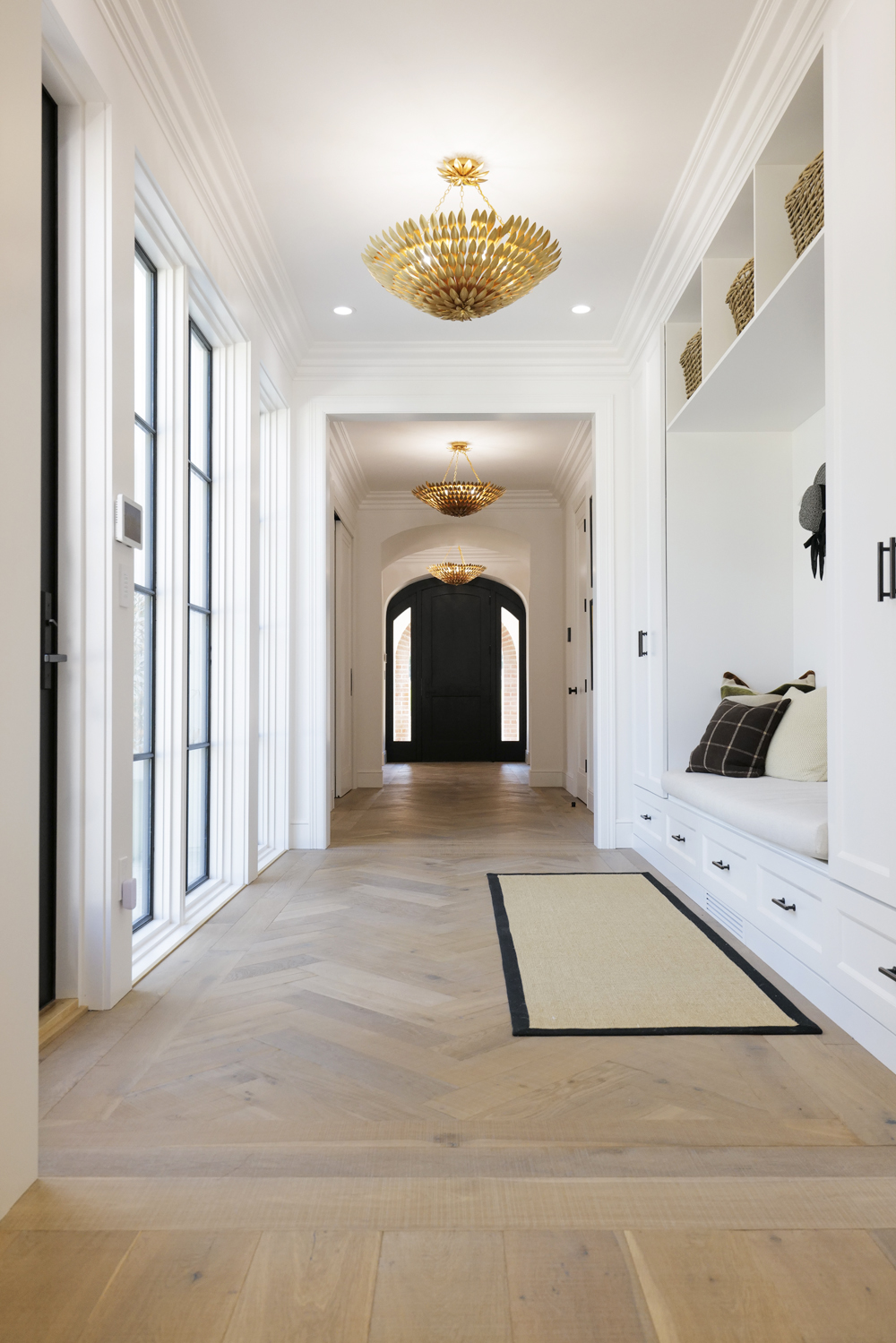 The bright whites and dark accents are the perfect combo for this expansive hallway that comes complete with its own mudroom-meets-cubby nook