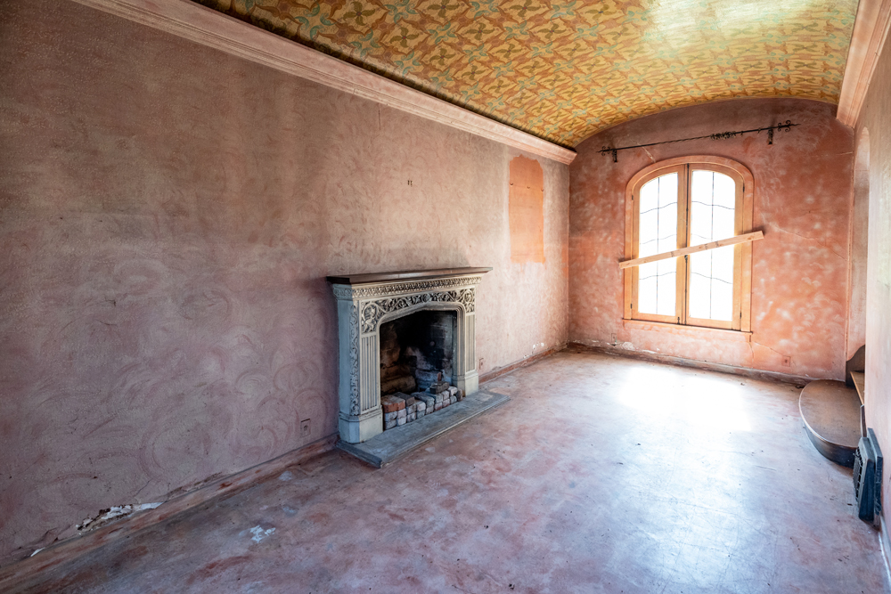 An original historic dining room with a sloped painted ceiling and original fireplace