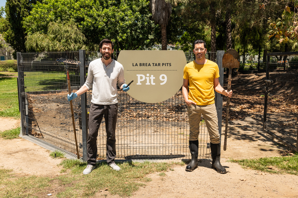 Drew and Jonathan Scott, holding rakes and shovels, stand outside the La Brea Tar Pits in Los Angeles