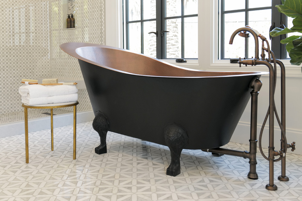 A gorgeous matte black claw foot tub with brass hardware and exposed pipes