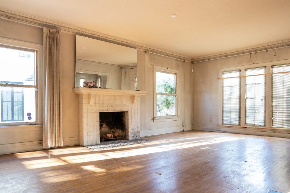 A rundown living room in a Los Angeles mansion, complete with fireplace