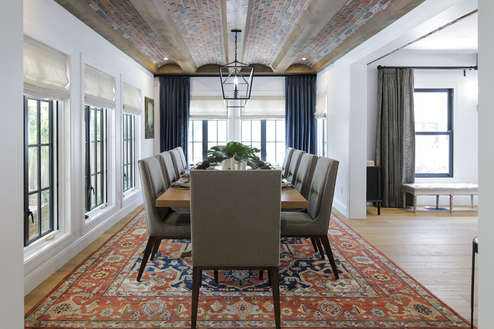 A renovated dining room with a wall of windows, four-barrel vault ceiling and modern light fixtures