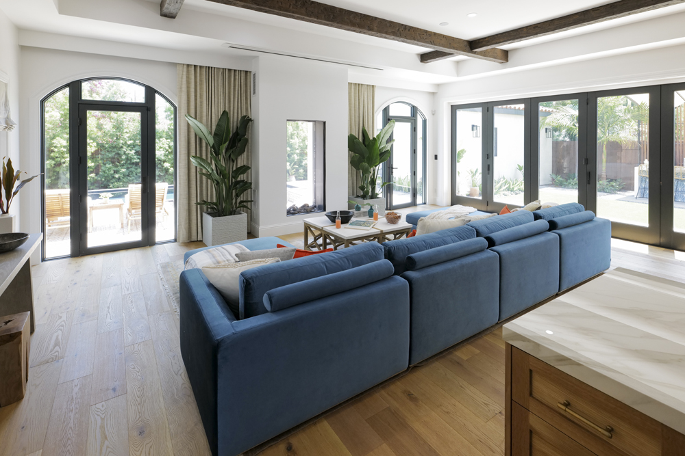 A living space off the kitchen with a pop of blue with the couch and a see-through fireplace