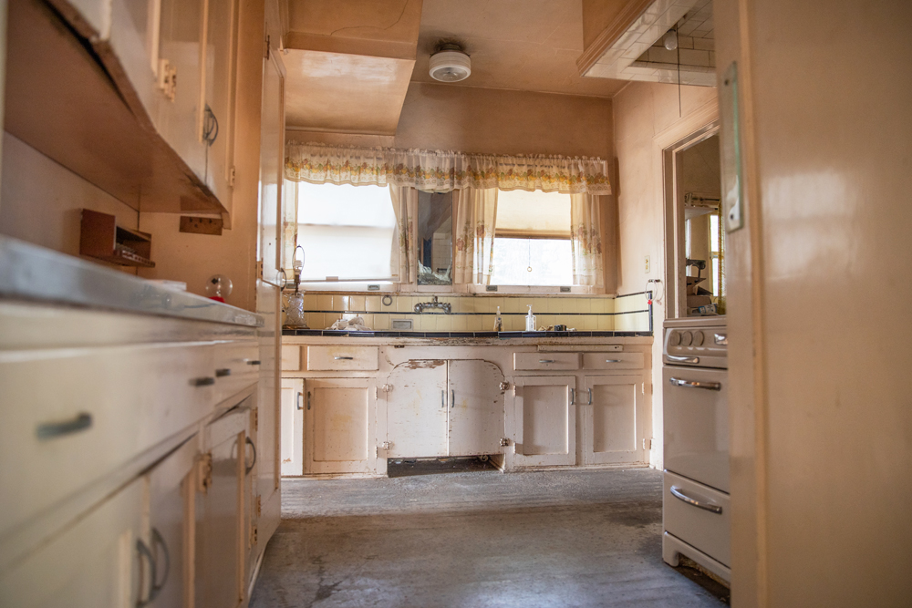 A tiny outdated beige kitchen with minimal natural light