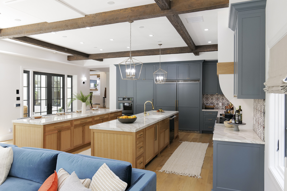 A blue and white modern kitchen with plenty of storage and wood ceiling beams