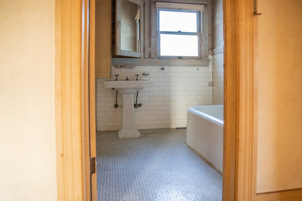 An old, outdated, narrow bathroom off the main bedroom