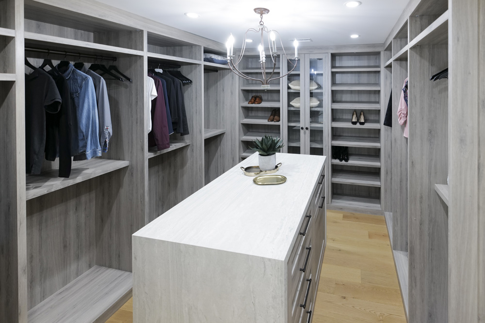 A modern walk-in closet with stone island and plenty of built-in storage