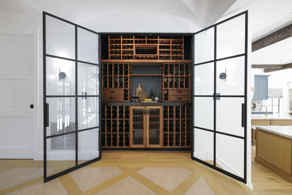 A spacious walk-in wine rack pantry with large doors and space for hundreds of bottles