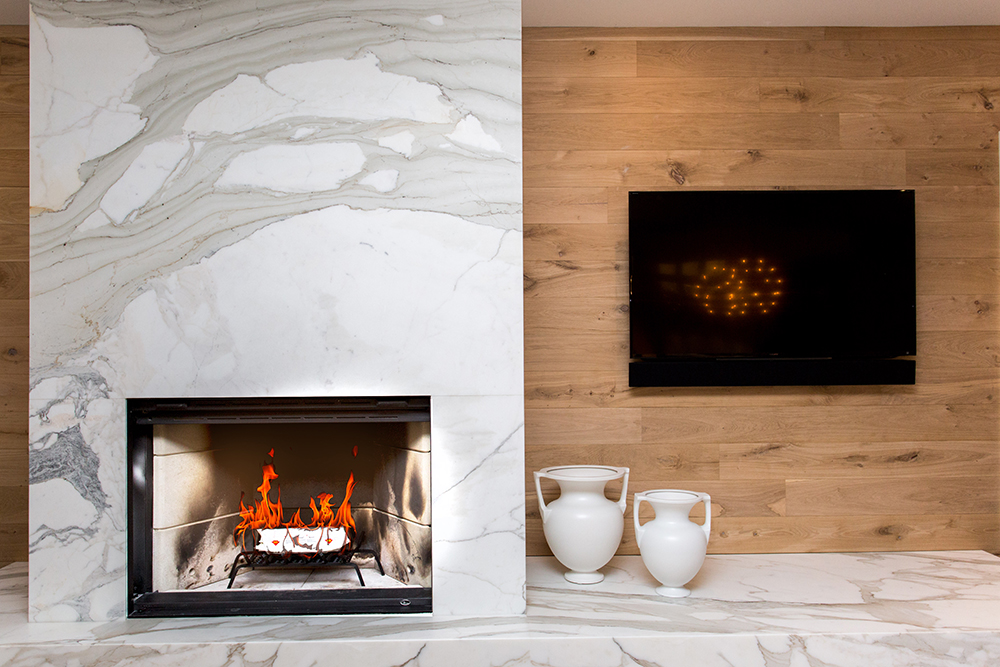 White marble fireplace, wooden wall with a flat screen TV on the wall