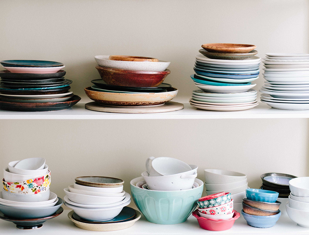 Plates and bowls stacked on a white shelf