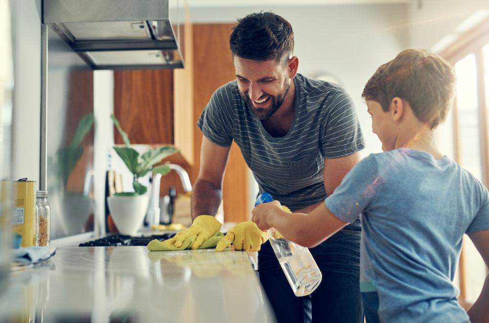 man and child cleaning counter in kitchen