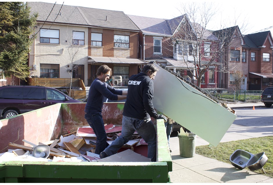 Two men hoisting a fridge off a truckbed.
