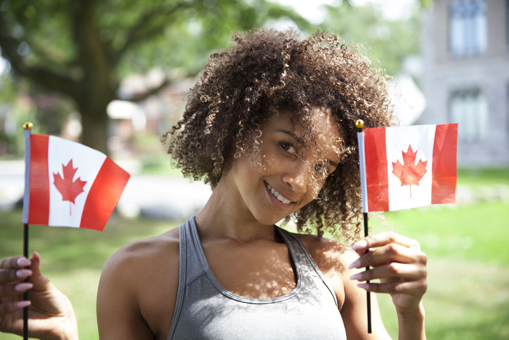 A young woman holds up two mini Canadian flags