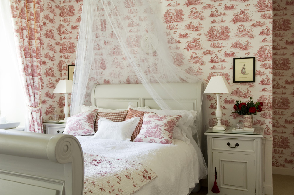 A delicate pink and white bedroom with transparent canopy curtain