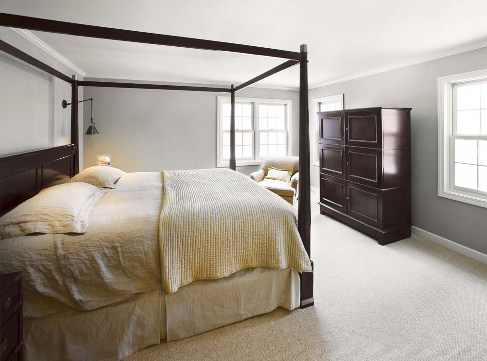 A classic curtain-free four-cornered canopy bed in a minimalist bedroom
