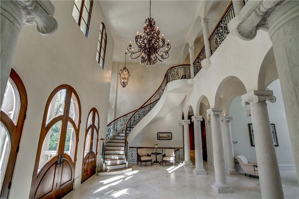 A sweeping front foyer with Corinthian columns, spiral staircase and over-sized chandelier