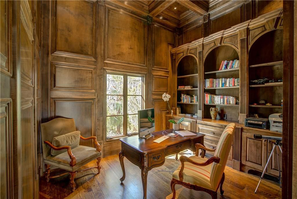 A wood-panelled home office with high ceilings and plenty of bookshelves