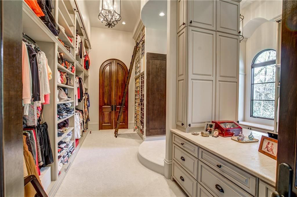 Massive ensuite walk-in closet with floor-to-ceiling shelving that can be reached via wood ladder
