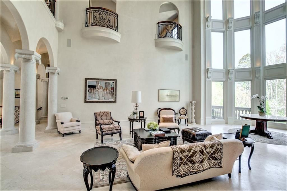 A high-ceilinged living room with floor-to-ceiling windows and Renaissance-style furniture