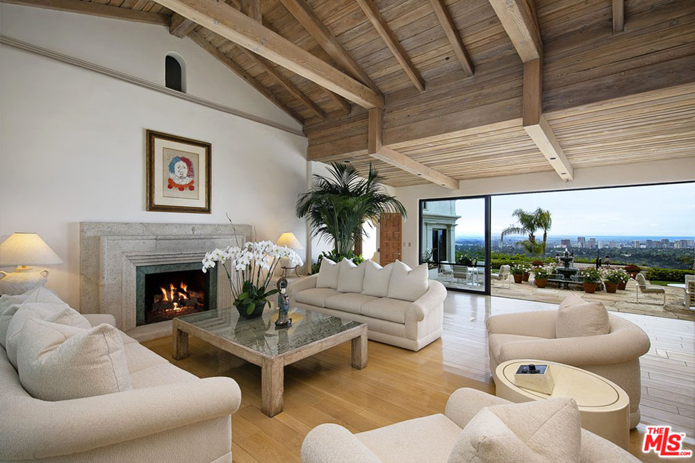 An open-concept living room with a wood-burning fireplace and direct doorway to a back balcony overlooking the city