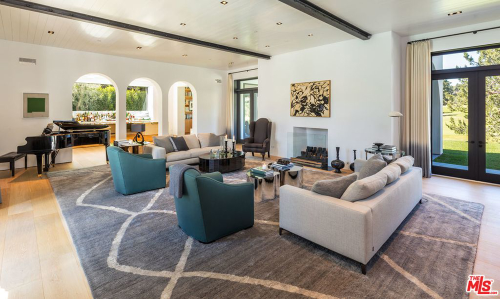 A sprawling living room off to the side of a bar with a fireplace and seating area that overlooks the nearby golf course