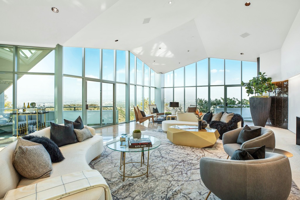 A glass mansion overlooking the city with mid-century modern furniture and an area rug