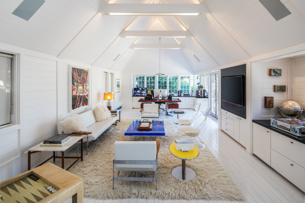 Part basement den, part home office, this monochromatic space includes pops of colours and high-vaulted ceilings