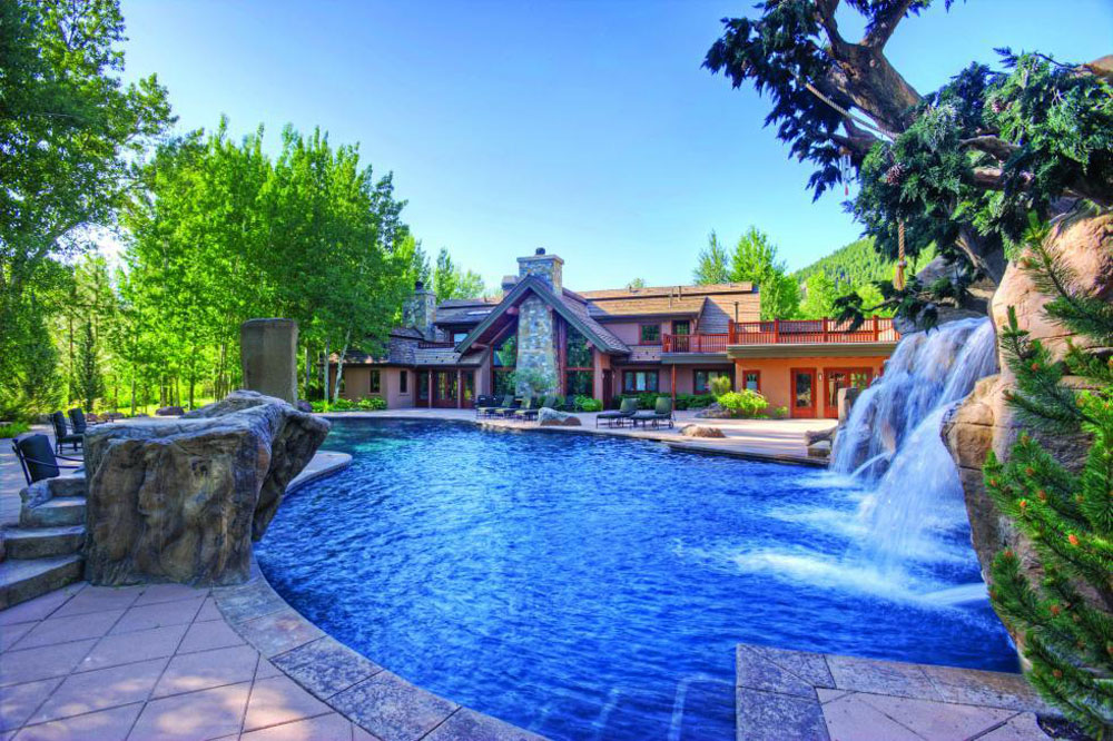 A vivid blue swimming pool with a waterfall and rock formation on the backyard grounds of Bruce Willis' former mansion