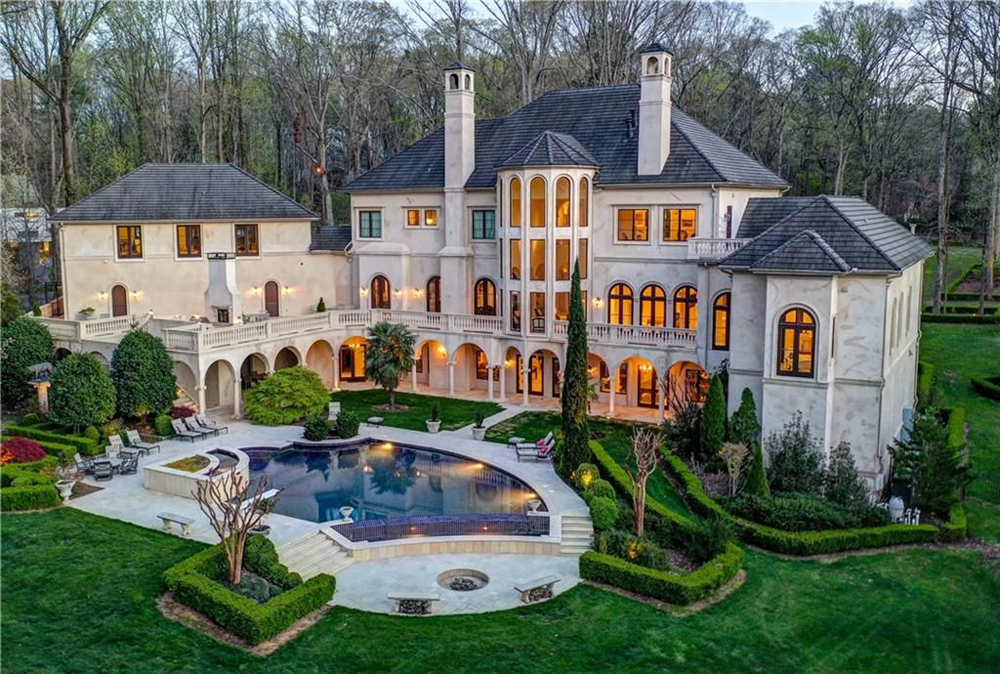 Perfectly manicured landscaping in an expansive backyard with an infinity pool and European-style hedges