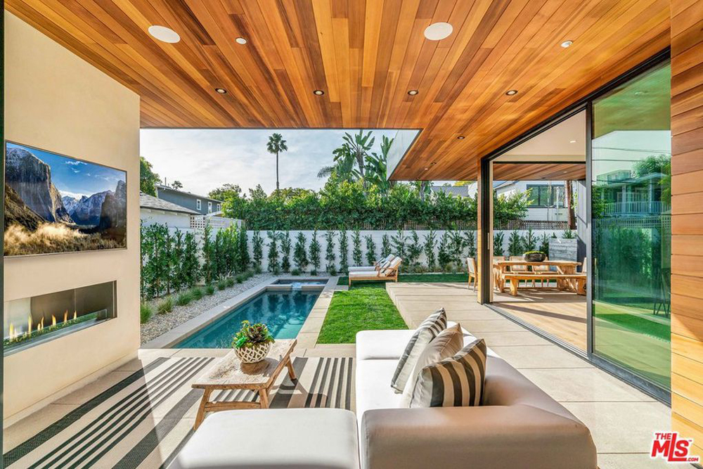 An outdoor gas fireplace and widescreen television are the focal points of the covered patio area that overlooks a lap pool