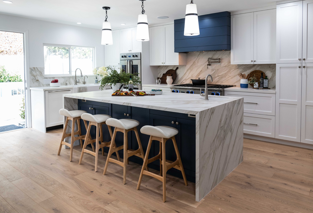 The renovated kitchen were the dining room used to be with a sintered marble island, navy blue under-storage and modern appliances and cabinets