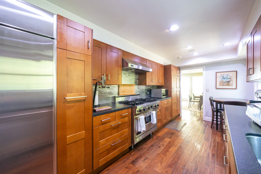 A narrow, outdated kitchen with blond wood cabinetry and not much natural light