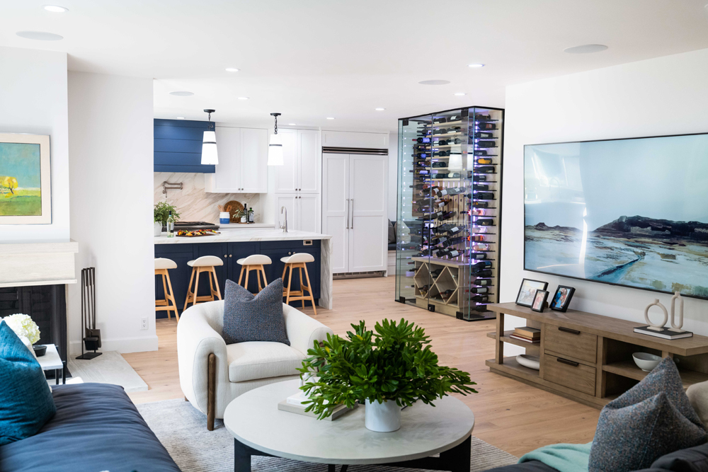 The open-concept space after - with modern furniture, updated fireplace and a glass floor-to-ceiling wine cabinet