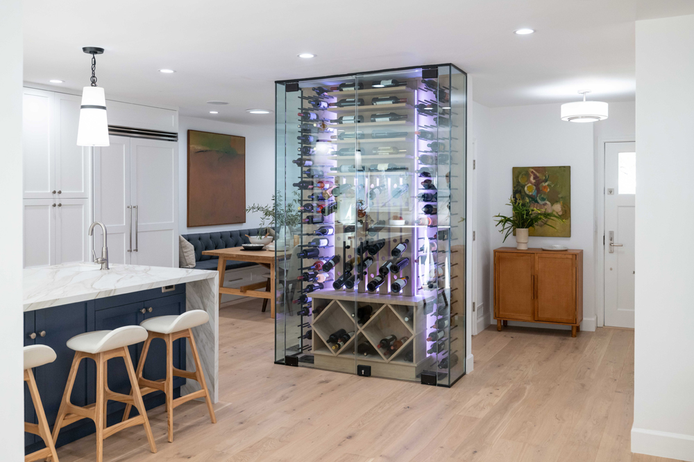 A fully-stocked floor-to-ceiling glass wine cabinet in the open space between the renovated kitchen and dining room