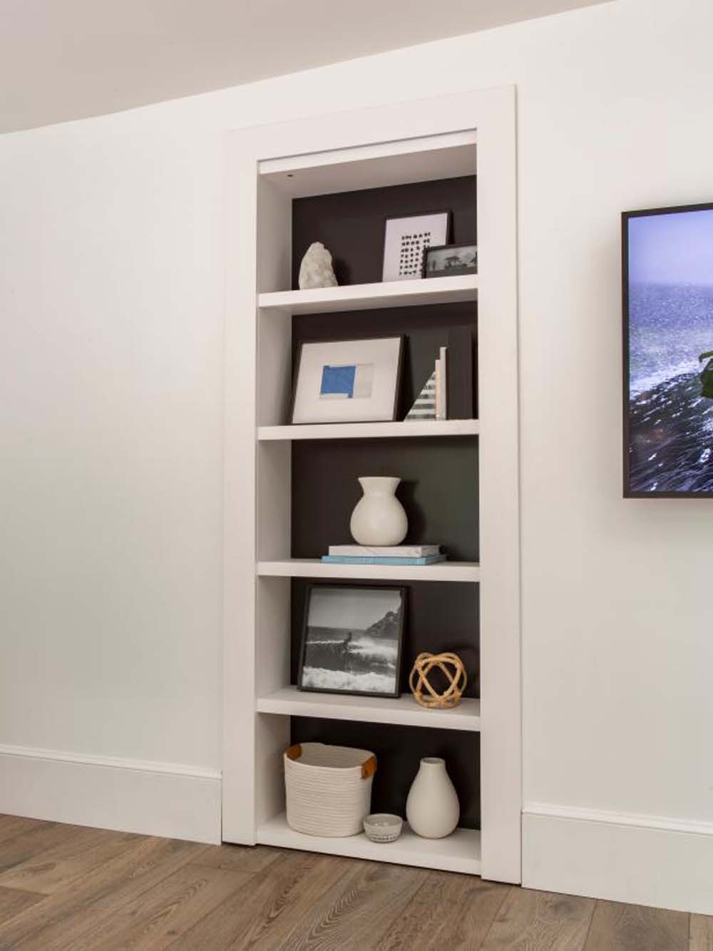 A narrow wall storage shelf that opens into a larger storage room