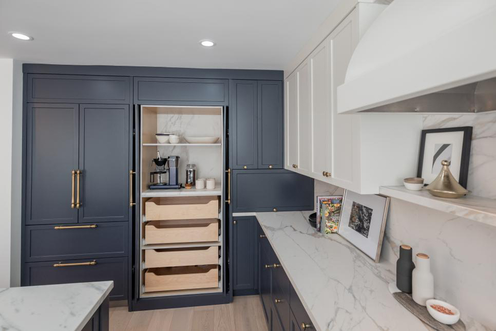 A two-toned kitchen, with white upper cabinets, blue lowers and antique brass hardware to boot