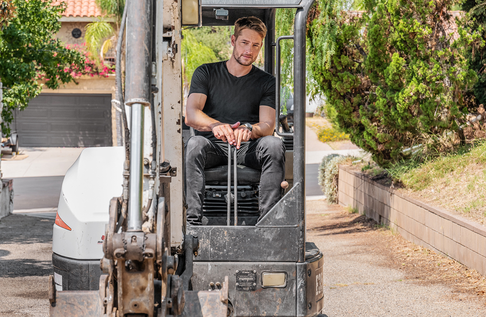 Justin Hartley drives a digger to help gut the old swimming pool