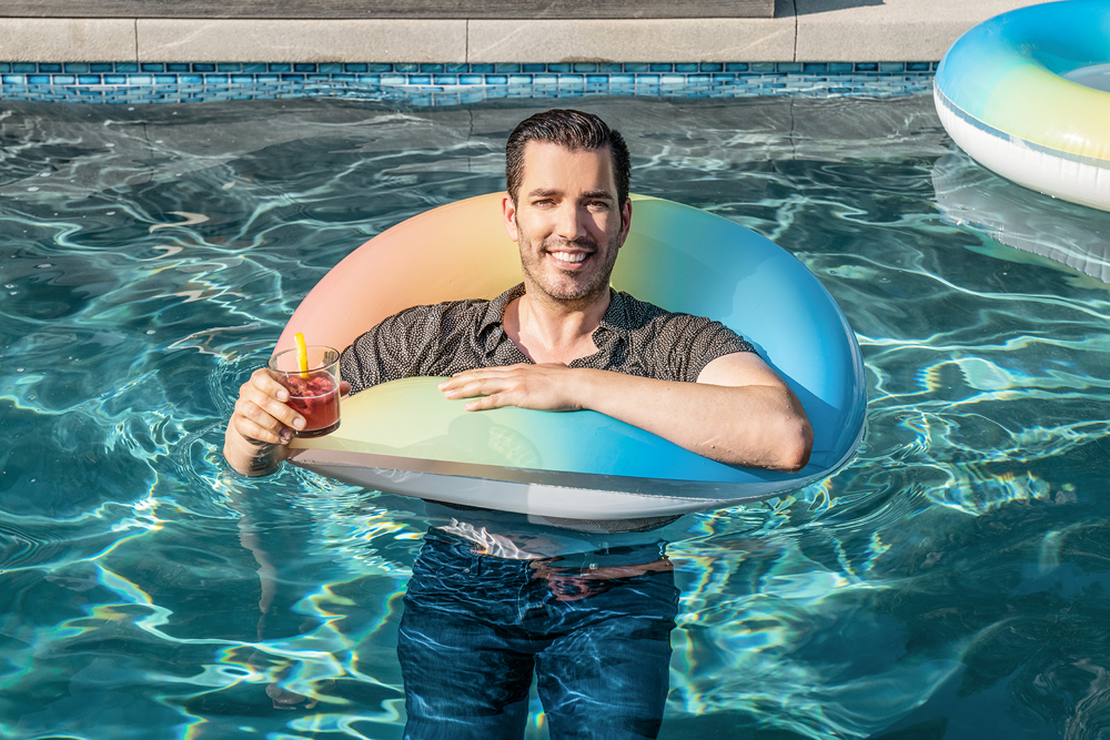 Jonathan Scott, fully clothed enjoys a mixed drink while using a floating device in the swimming pool after he was thrown in