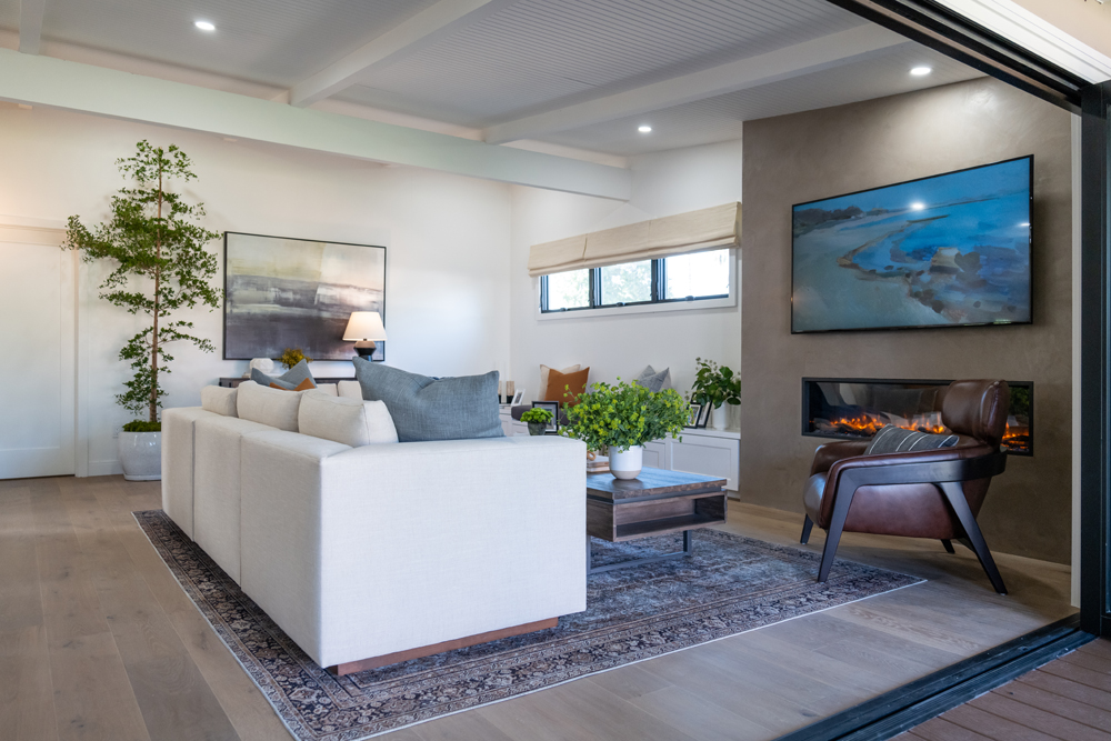 A renovated living room with greenery, gas fireplace and The Frame television set