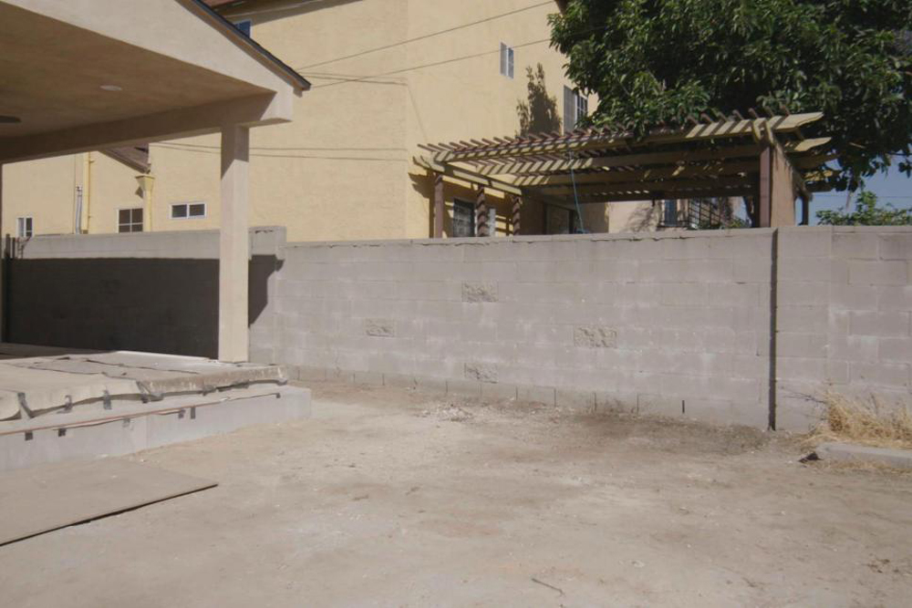A barren, concrete backyard prior to renovation