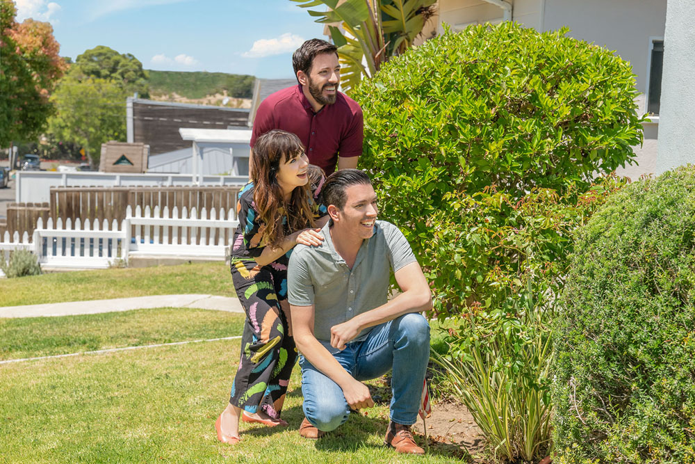 Zooey Deschanel crouches behind some bushes with Drew and Jonathan Scott