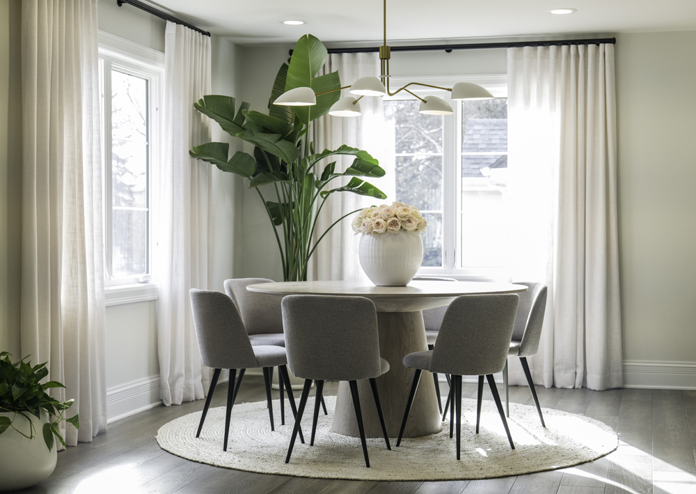 A chic dining room features a round table for six and a playful light fixture