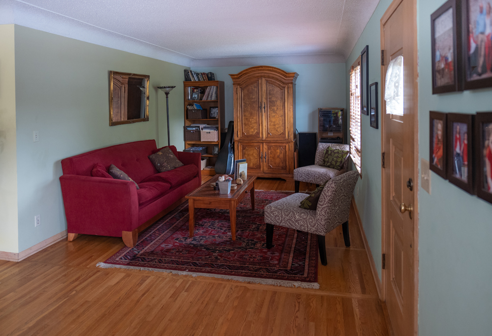 A small, outdated living room with area rug and oversized furniture