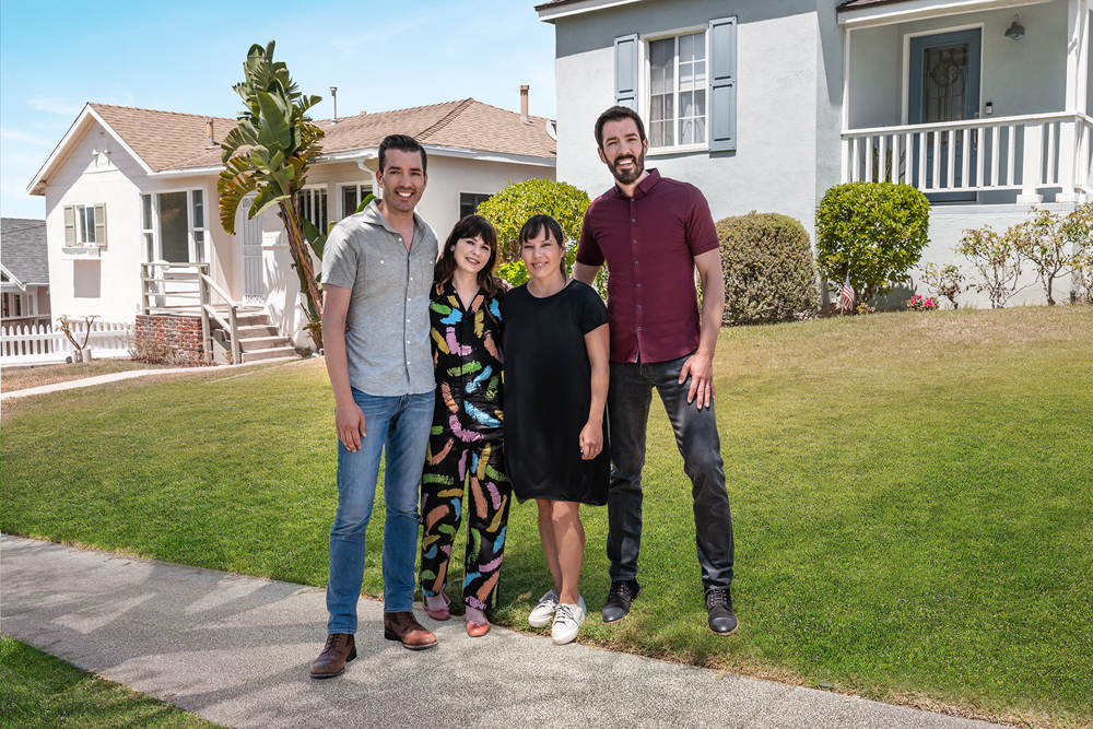 Jonathan Scott and Drew Scott pose on either side of Zooey Deschanel and her friend Sarah on Sarah's front lawn