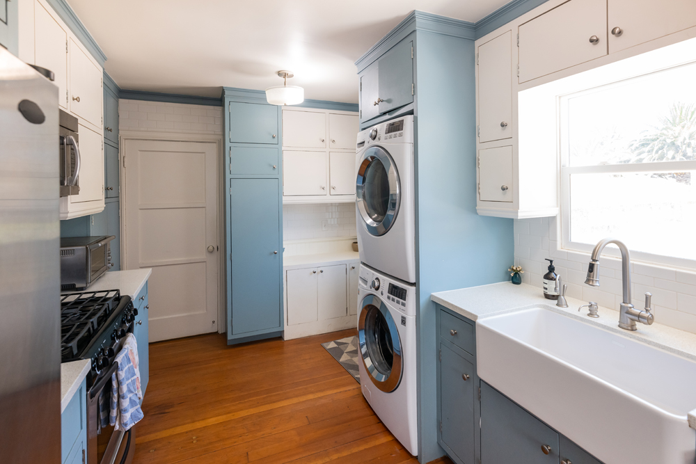 The pre-renovation kitchen with a stacked washer-dryer in the kitchen next to the farmhouse sink